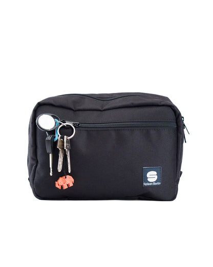 Vorderansicht der schwarzen Crossbody-Tasche von Spleen Berlin mit sichtbarem Reißverschluss; im Vorderfach steckt ein Schlüsselbund. Vegane 3,5-Liter-Umhängetasche im urbanen Stil, auch als Lenkertasche fürs Fahrrad geeignet.
@Spleen Berlin