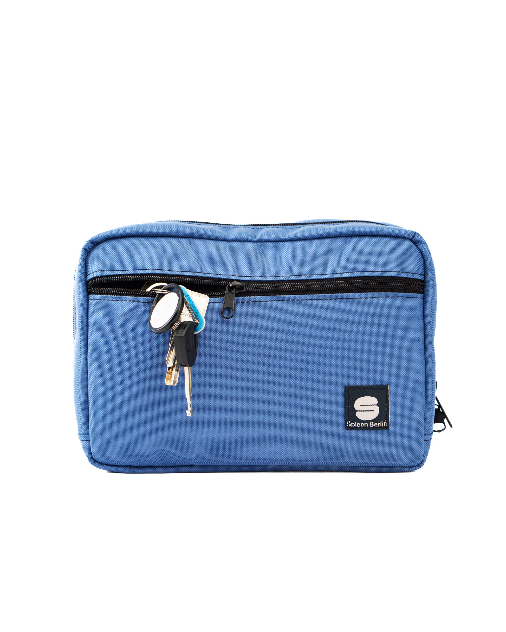 Seitliche Ansicht der hellblauen Crossbody-Bag „Iceblue“ von Spleen Berlin mit sichtbarer Fronttasche und Zipper; im Frontfach steckt ein Schlüssel. Vegane, stylische 3,5-Liter-Umhängetasche im urbanen Look, auch als Lenkertasche fürs Fahrrad nutzbar.
@Spleen Berlin