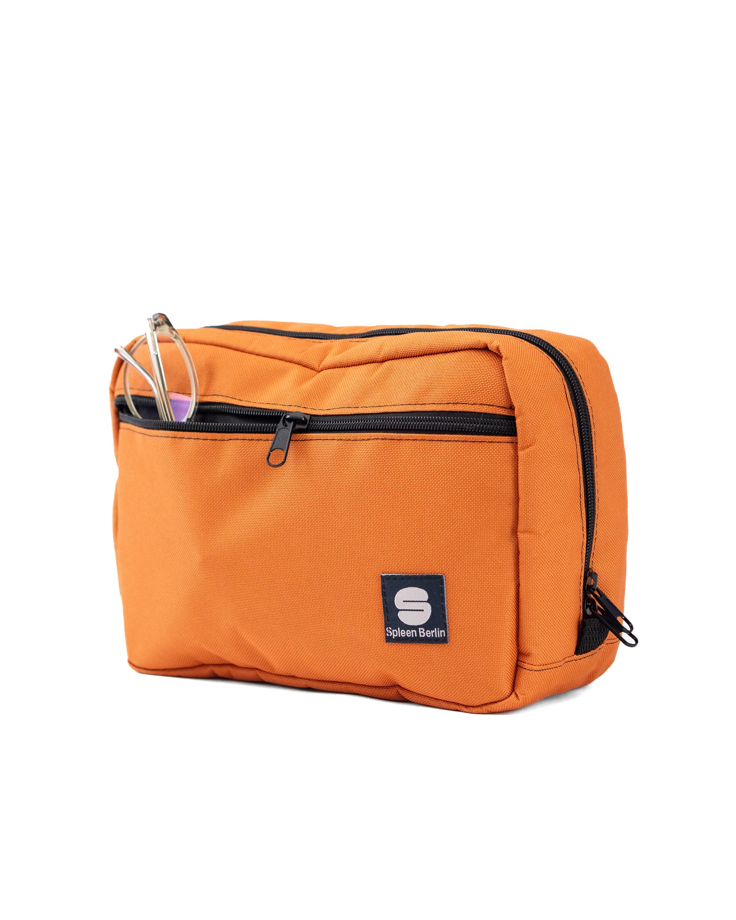 Orangefarbene Crossbody-Bag „Skandinavian Orange“ von Spleen Berlin in Vorderansicht mit sichtbarer Fronttasche und Zipper; in der Fronttasche steckt eine Brille. Vegane 3,5-Liter-Umhängetasche im urbanen Stil, auch als Lenkertasche fürs Fahrrad nutzbar. @Spleen Berlin