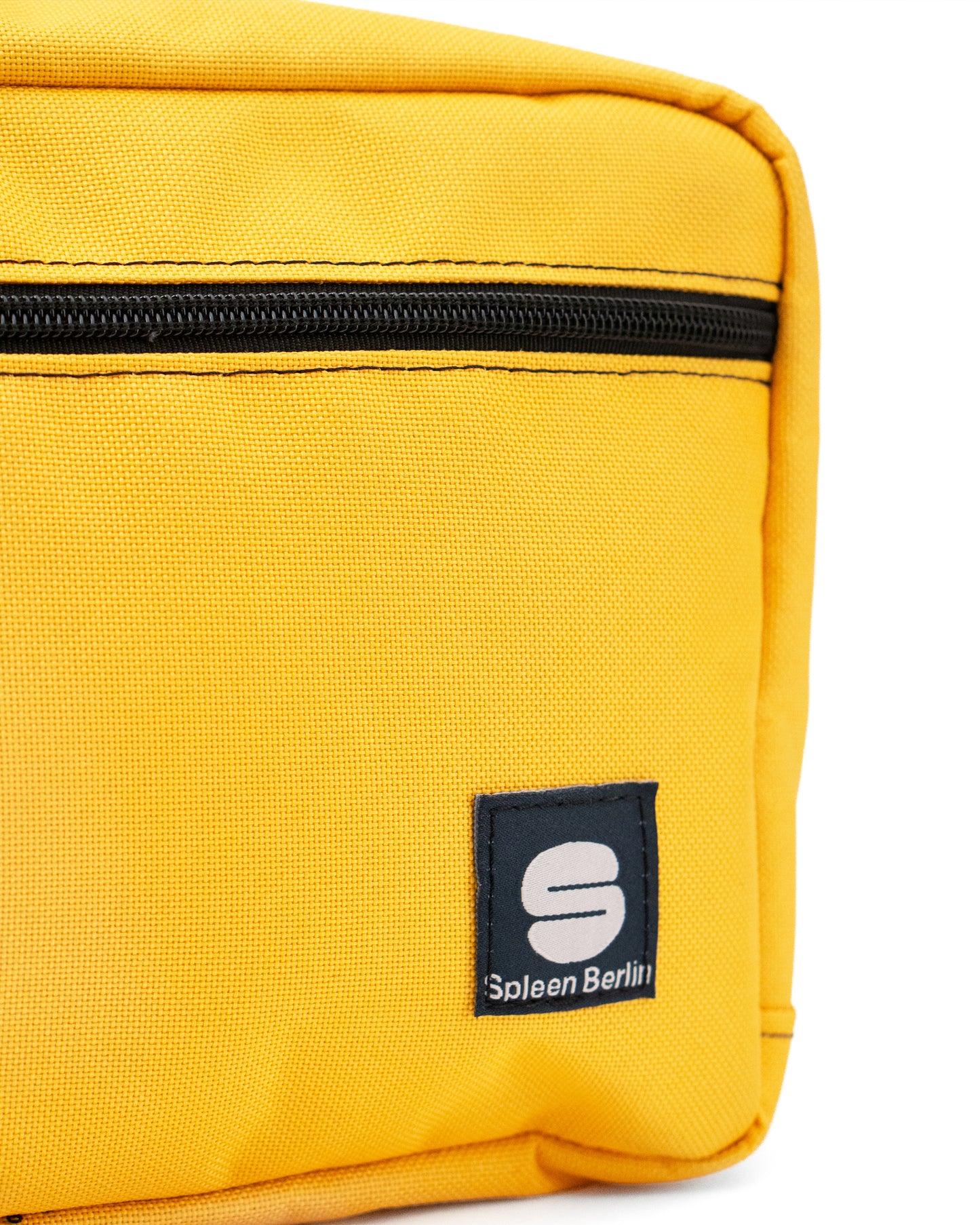Detailansicht der gelben Crossbody-Bag „Sunrise“ von Spleen Berlin mit sichtbarem Zipper; vegane 3,5-Liter-Umhängetasche im urbanen Stil, auch als Lenkertasche fürs Fahrrad geeignet. @Spleen Berlin