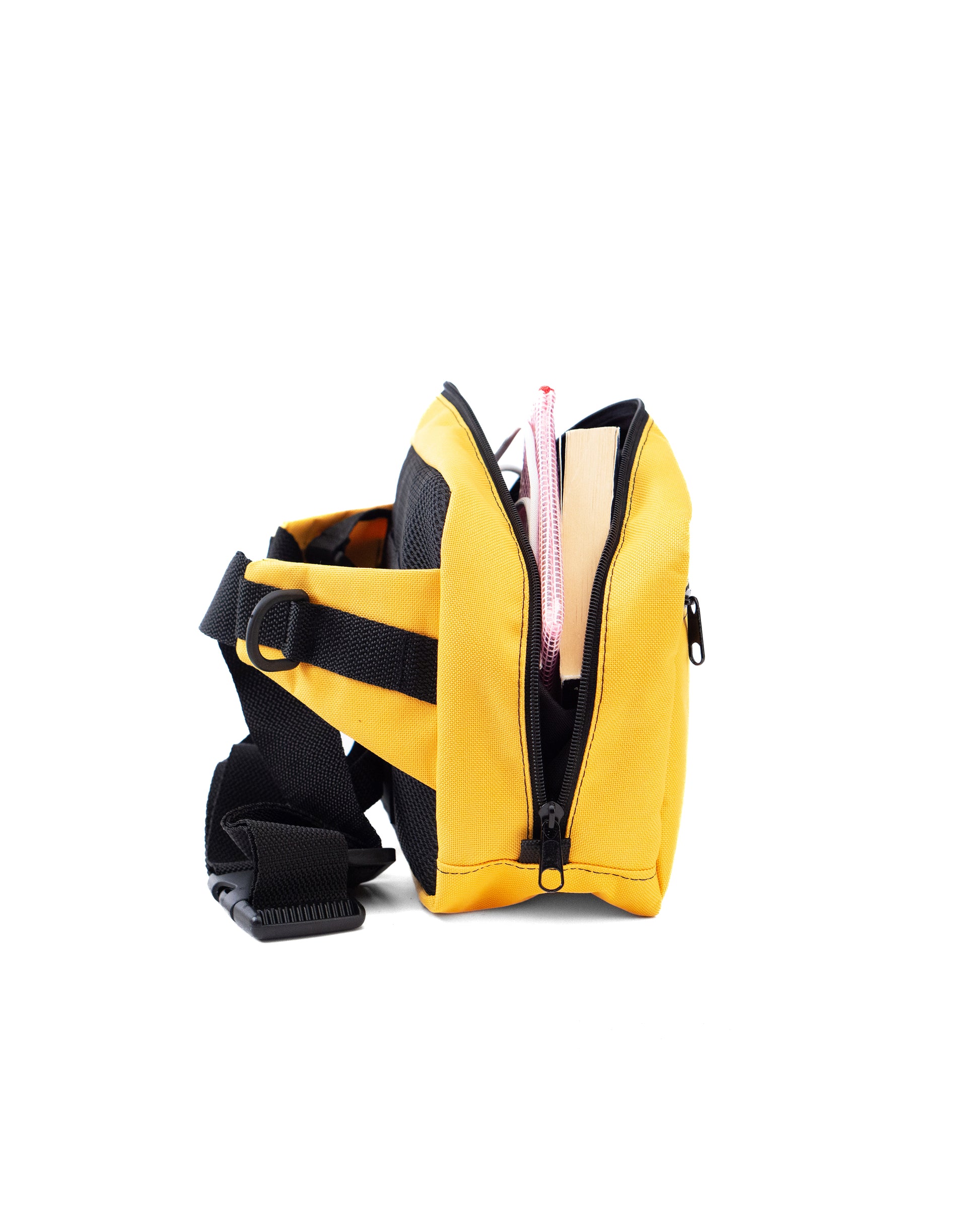 Geöffnete gelbe Crossbody-Bag „Sunrise“ von Spleen Berlin in seitlicher Ansicht; im Inneren sichtbare Gegenstände zur Darstellung der Füllmenge einer 3,5-Liter-veganen, urbanen Umhängetasche, die auch als Lenkertasche fürs Fahrrad nutzbar ist. @Spleen Berlin