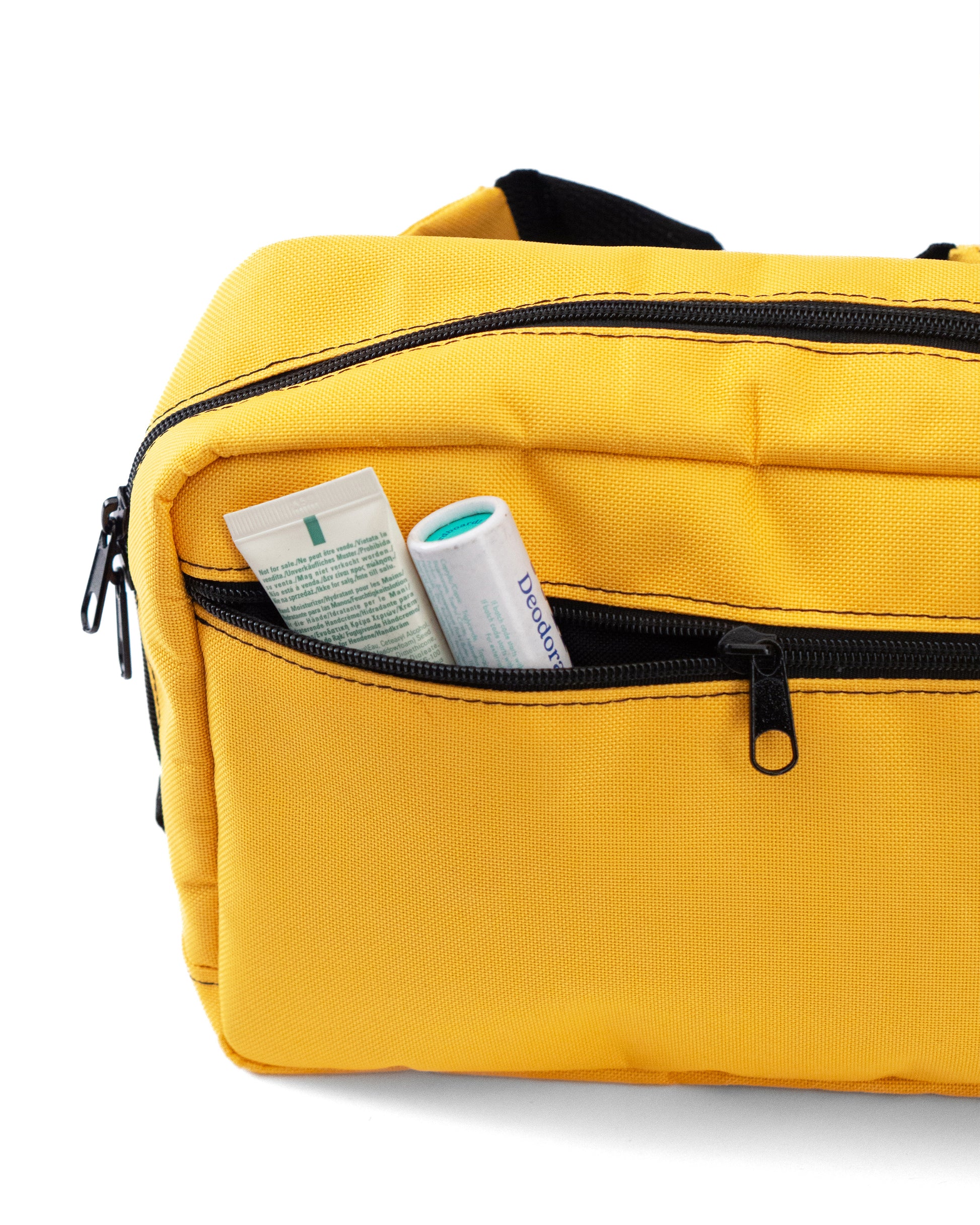 Crossbody-Bag „Sunrise“ von Spleen Berlin in Gelb, gezeigt mit geöffneter Fronttasche, in der verschiedene Gegenstände stecken; vegan, urbanes Design, 3,5-Liter-Fassungsvermögen, auch als Lenkertasche fürs Fahrrad nutzbar. @Spleen Berlin