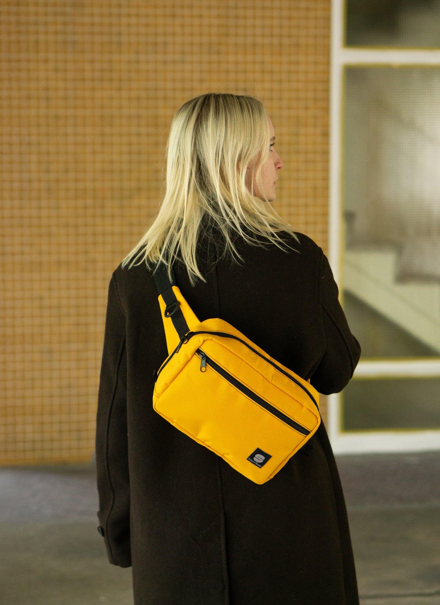 Crossbody-Bag Sunrise von Spleen Berlin – stylische Fahrrad- und Alltagstasche in sonnigem Design, getragen von einer Frau im urbanen Stil. @Spleen Berlin