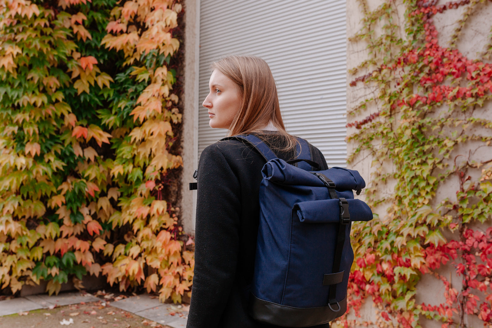 BOB  Rucksack in Marineblau von Spleen Berlin getragen im Alltag vor herbstlicher Blätterwand, hybrid nutzbar als Fahrradrucksack & Fahrradtasche, vegan.
©Spleen Berlin