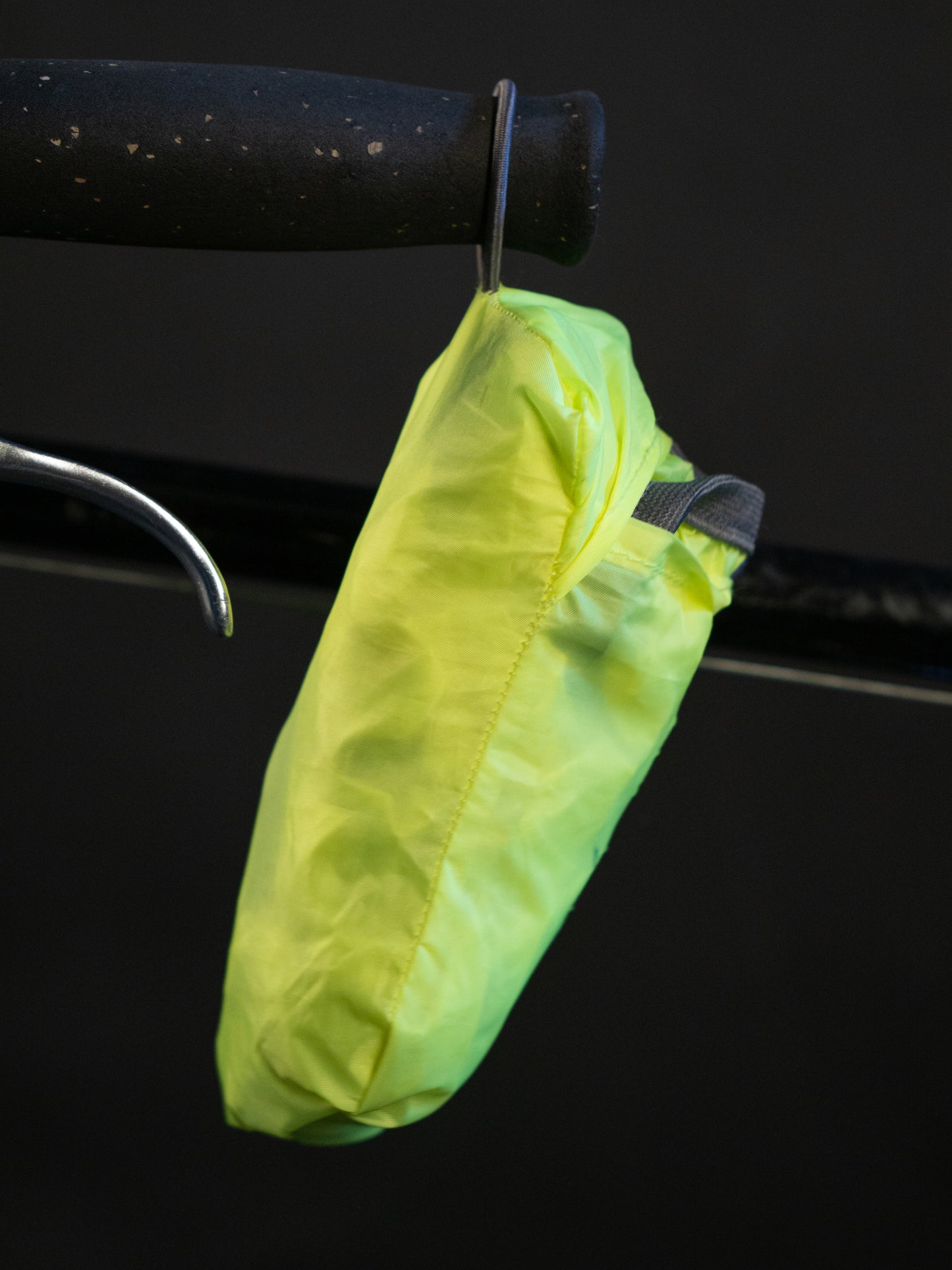 Regenhülle Neongelb verpackt am Lenker am Lenker haengend bei Nacht.