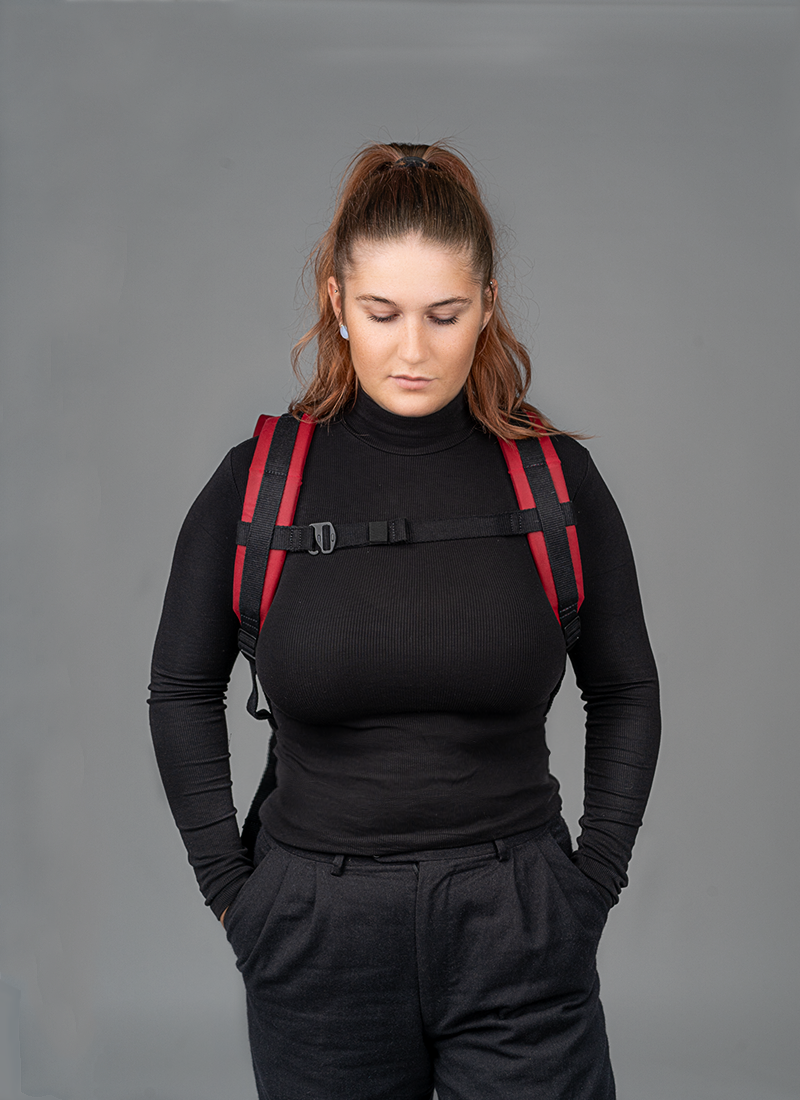 Roter Rucksac Bob in•
 der•
 Vorderansicht, getragen von
 einer jungenPerson. Deutlich zu•
 erkennen sind die ergonomisch gepolsterten Schulterträger und der geschlossene Brustgurt der für optimalen Halt und angenehmen Sitz sorgt ideal für den Alltag oder den Weg mit dem Fahrrad.
©Spleen Berlin