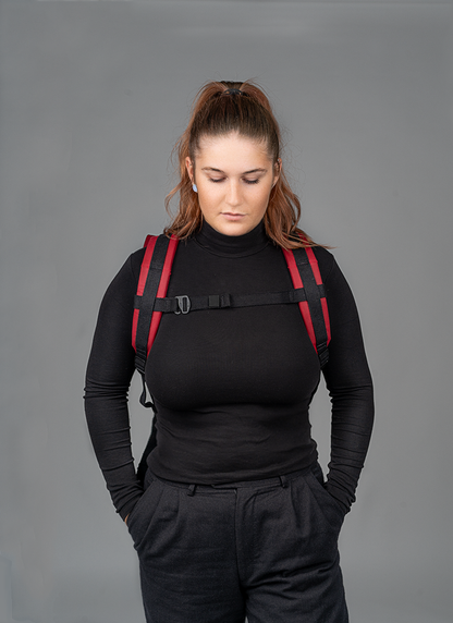 Roter Rucksac Bob in•
 der•
 Vorderansicht, getragen von
 einer jungenPerson. Deutlich zu•
 erkennen sind die ergonomisch gepolsterten Schulterträger und der geschlossene Brustgurt der für optimalen Halt und angenehmen Sitz sorgt ideal für den Alltag oder den Weg mit dem Fahrrad.
©Spleen Berlin