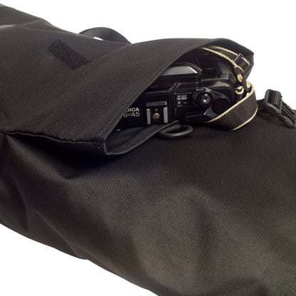 Bob -Black vordere Rolltop-Tasche ausgerollt mit eingesteckter Kamera, zeigt vielseitige Fronttaschen des urbanen Fahrradrucksacks von Spleen Berlin ©Spleen Berlin
